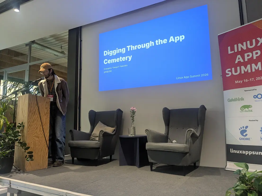 Me on stage speaking on a microphone while there's a projection behind me with the title 'Digging through the app cemetery'